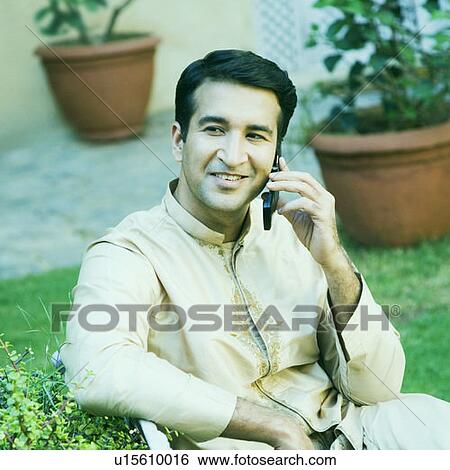Stock Photograph - Mid adult man talking on a mobile phone and smiling. Fotosearch