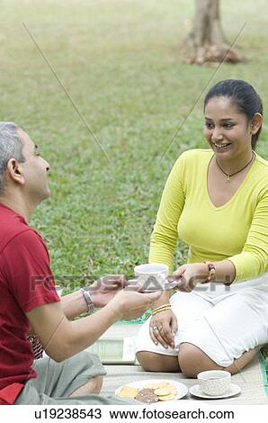 Mid adult woman giving a tea cup to a mid adult man and smiling View Large Photo Image Stock Image - Mid adult woman giving a tea cup to a mid adult man and smiling. Fotosearch