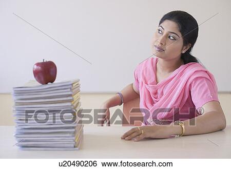 Stock Photograph - Mid adult woman sitting at a desk. Fotosearch