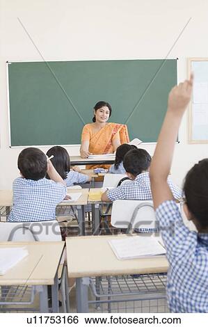 Stock Photograph - Mid adult woman teaching students in a classroom. Fotosearch