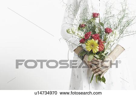 Stock Image - Mid section view of a woman holding a bouquet of flowers. Fotosearch