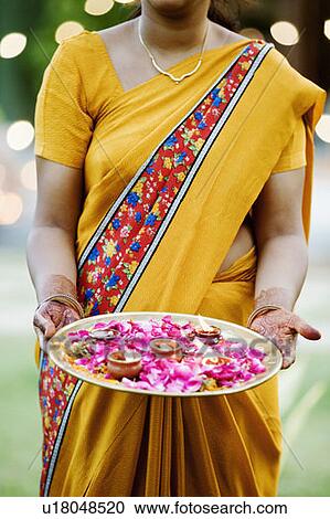 Mid section view of a woman holding oil lamps and Rose petals in a plate View Large Photo Image Stock Image - Mid section view of a woman holding oil lamps and Rose petals in a plate. Fotosearch