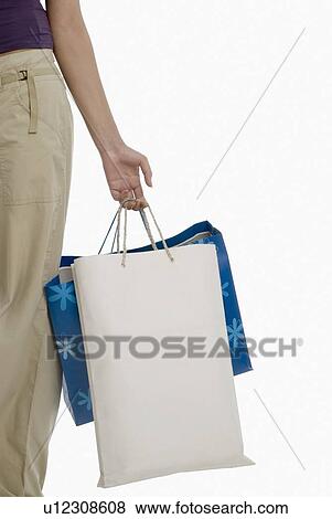 Mid section view of a woman holding shopping bags View Large Photo Image Stock Photo - Mid section view of a woman holding shopping bags. Fotosearch
