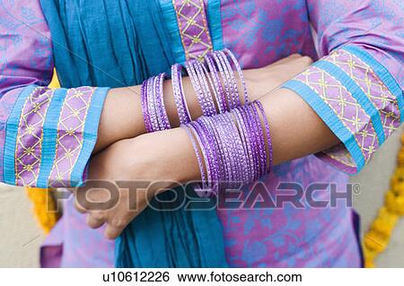 Mid section view of a woman wearing bangles View Large Photo Image Stock Photograph - Mid section view of a woman wearing bangles. Fotosearch