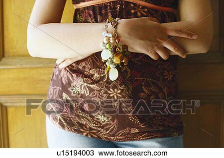 Mid section view of a young woman standing with her arms crossed View Large Photo Image Stock Image - Mid section view of a young woman standing with her arms crossed. Fotosearch