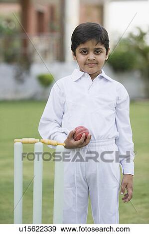 Stock Photo - Portrait of a boy holding a cricket ball and smiling. Fotosearch