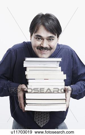 Portrait of a businessman holding a stack of books View Large Photo Image Stock Photo - Portrait of a businessman holding a stack of books. Fotosearch