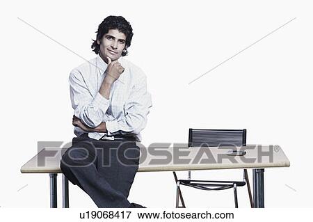 Stock Photo - Portrait of a businessman sitting on the table. Fotosearch