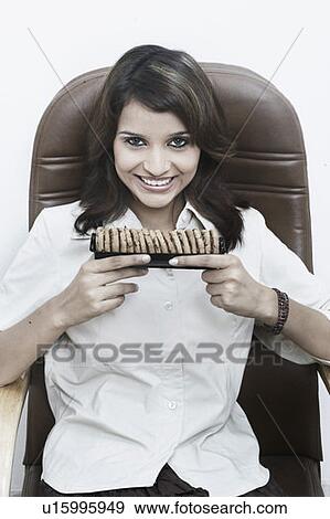 Stock Photo - Portrait of a businesswoman holding cookies. Fotosearch