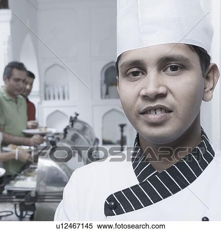 Stock Photography - Portrait of a chef with two mid adult men having food behind him. Fotosearch