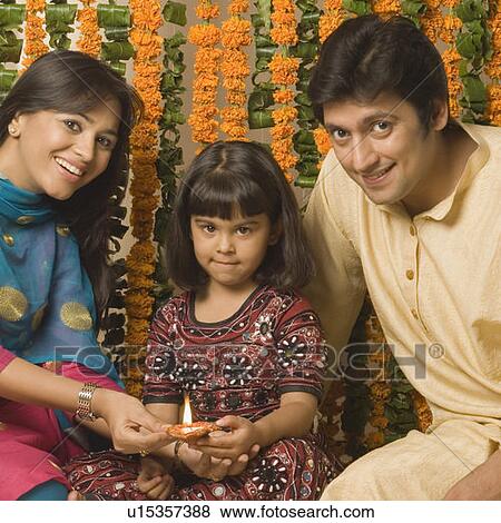 Portrait of a couple sitting with their daughter behind oil lamps and smiling View Large Photo Image Stock Photo - Portrait of a couple sitting with their daughter behind oil lamps and smiling. Fotosearch