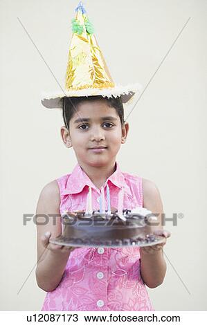 Stock Image - Portrait of a girl holding a birthday cake and smiling. Fotosearch