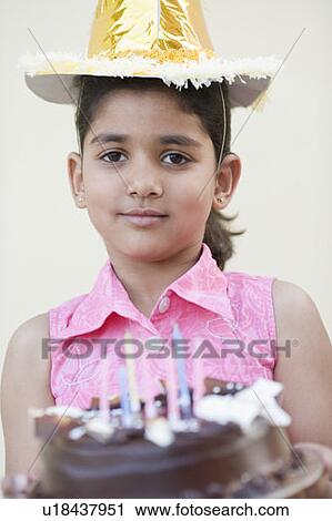 Stock Image - Portrait of a girl holding a birthday cake and smiling. Fotosearch