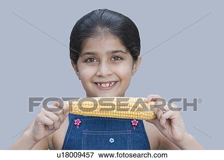 Portrait of a girl holding a corn cob and smiling View Large Photo Image Stock Photo - Portrait of a girl holding a corn cob and smiling. Fotosearch