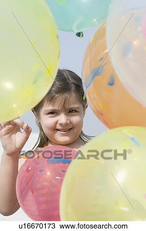 Stock Image - Portrait of a girl holding balloons and smiling. Fotosearch