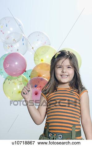 Portrait of a girl holding balloons and smiling View Large Photo Image Stock Photo - Portrait of a girl holding balloons and smiling. Fotosearch