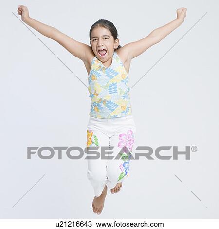 Stock Image - Portrait of a girl jumping with her arms raised. Fotosearch