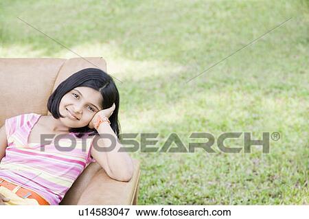 Portrait of a girl sitting in an armchair and smiling View Large Photo Image Stock Photo - Portrait of a girl sitting in an armchair and smiling. Fotosearch