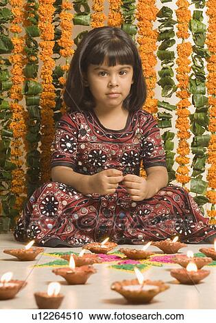 Stock Image - Portrait of a girl sitting in front of oil lamps. Fotosearch