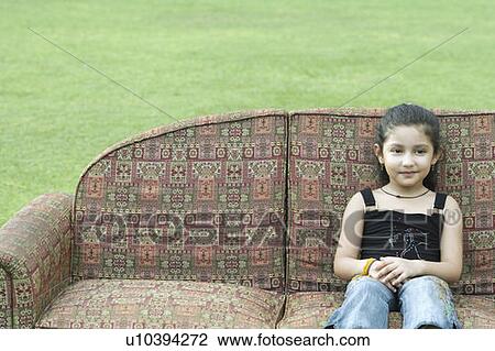 Stock Image - Portrait of a girl sitting on a couch outdoors. Fotosearch
