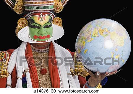 Stock Image - Portrait of a Kathakali dance performer holding a globe. Fotosearch