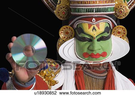 Stock Image - Portrait of a Kathakali dance performer holding a CD. Fotosearch