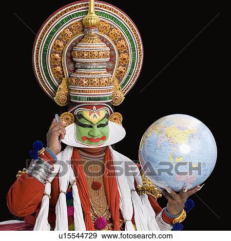 Stock Photo - Portrait of a Kathakali dance performer holding a globe and a mobile phone. Fotosearch