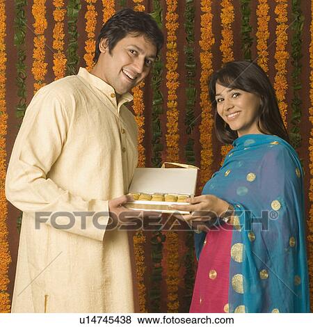 Stock Photo - Portrait of a mid adult man and a young woman holding a sweet box. Fotosearch