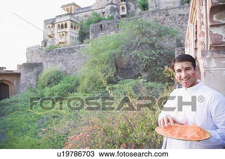 Portrait of a mid adult man holding a plate of powder paint and smiling, Neemrana Fort Palace, Neemrana, Alwar, Rajasthan, India View Large Photo Image Stock Image - Portrait of a mid adult man holding a plate of powder paint and smiling, Neemrana Fort Palace, Neemrana, Alwar, Rajasthan, India. Fotosearch