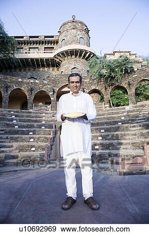 Portrait of a mid adult man holding a plate of powder paint, Neemrana Fort Palace, Neemrana, Alwar, Rajasthan, India View Large Photo Image Stock Photo - Portrait of a mid adult man holding a plate of powder paint, Neemrana Fort Palace, Neemrana, Alwar, Rajasthan, India. Fotosearch