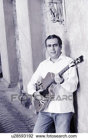 Stock Image - Portrait of a mid adult man playing a guitar. Fotosearch
