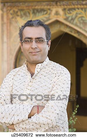 Stock Image - Portrait of a mid adult man standing with his arms crossed, Neemrana Fort, Neemrana, Alwar, Rajasthan, India. Fotosearch