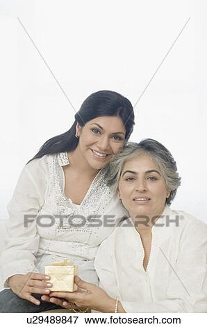 Stock Photo - Portrait of a mid adult woman giving a gift to her mother and smiling. Fotosearch