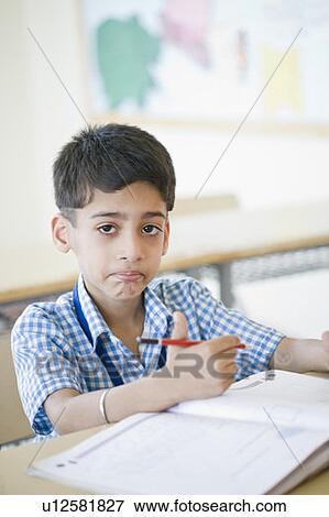 Stock Photo - Portrait of a schoolboy holding a pencil and smirking. Fotosearch