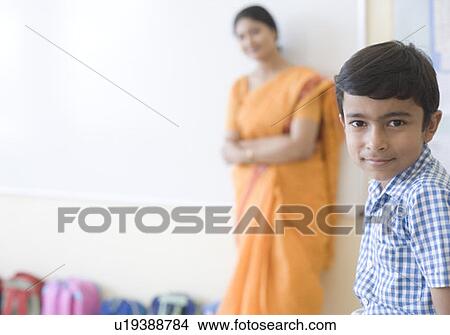 Picture - Portrait of a schoolboy with his teacher standing in the background. Fotosearch