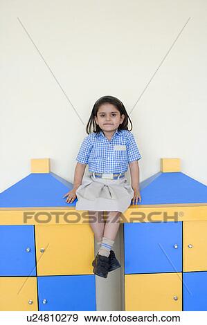 Stock Photo - Portrait of a schoolgirl sitting on a cabinet. Fotosearch