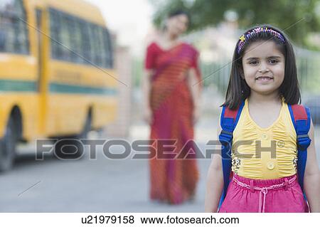 Stock Photo - Portrait of a schoolgirl smiling with her teacher standing in the background. Fotosearch