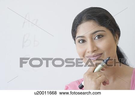Stock Photo - Portrait of a teacher holding a felt tip pen and smiling. Fotosearch