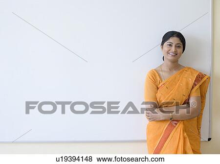 Stock Photo - Portrait of a teacher standing with her arms crossed and smiling. Fotosearch