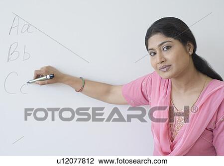 Stock Image - Portrait of a teacher writing on a whiteboard with a felt tip pen. Fotosearch