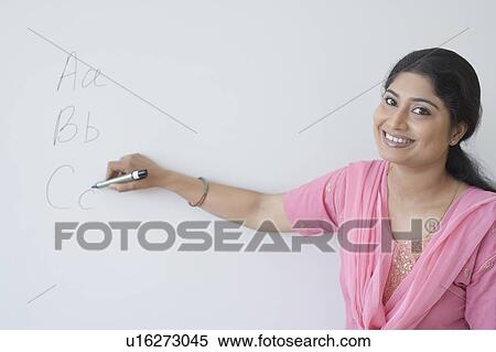 Stock Photography - Portrait of a teacher writing on a whiteboard with a felt tip pen. Fotosearch