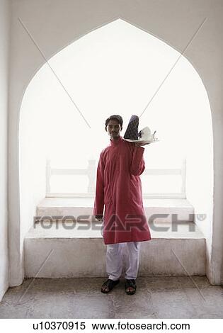 Stock Photography - Portrait of a waiter carrying a teapot in a tray. Fotosearch