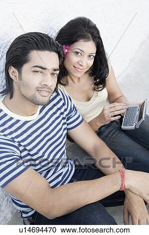 Portrait of a young couple leaning against a wall and smiling View Large Photo Image Stock Image - Portrait of a young couple leaning against a wall and smiling. Fotosearch