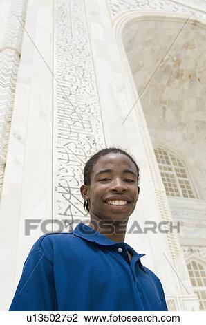 Stock Image - Portrait of a young man smiling, Taj Mahal, Agra, Uttar Pradesh, India. Fotosearch