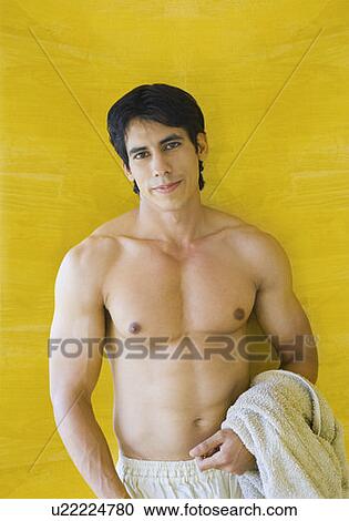 Portrait of a young man standing in front of a wall and smirking View Large Photo Image Stock Image - Portrait of a young man standing in front of a wall and smirking. Fotosearch