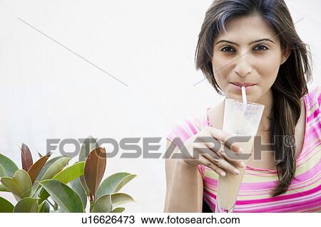 Stock Image - Portrait of a young woman drinking milkshake. Fotosearch