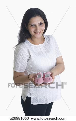 Stock Image - Portrait of a young woman holding a pair of baby booties. Fotosearch