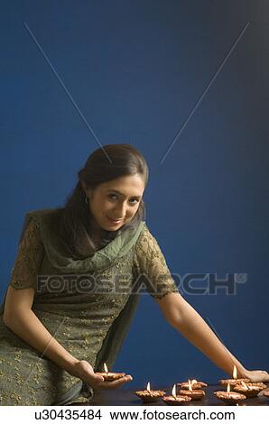 Picture - Portrait of a young woman holding an oil lamp and smiling. Fotosearch