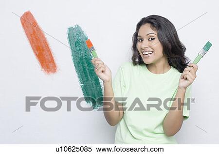 Portrait of a young woman holding paintbrushes and smiling View Large Photo Image Stock Photography - Portrait of a young woman holding paintbrushes and smiling. Fotosearch
