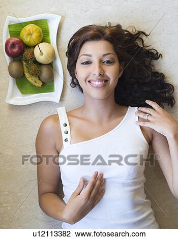 Portrait of a young woman lying near a fruit tray and smiling View Large Photo Image Stock Image - Portrait of a young woman lying near a fruit tray and smiling. Fotosearch